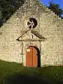 Porte Ouest de la chapelle avec pilastres, fronton et oculus.