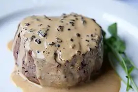 Vue rapprochée d’un steak au poivre dans une assiette.