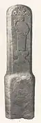 Stèle en pierre représentant un homme portant une toge et debout sur un socle entrant de boire dans une coupe.