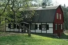Bâtiment ancien avec une façade rouge et une façade noire et blanche, avec un arbre au premier plan.