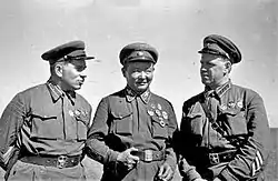 Photo noir et blanc de trois hommes en uniforme et portant des casquettes plates.