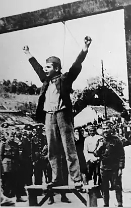 Un jeune homme en uniforme, sur le point d'être pendu, lève les deux bras en signe de défi.