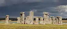 Photographie couleur de pierres taillées qui sont érigées verticalement sur un terrain herbeux.