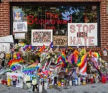 Drapeaux arc-en-ciel, fleurs et bougies au pied d'un bar de Stonewall.