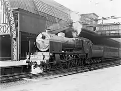 Un train de voyageur à quai dans la gare centrale, remorqué par une locomotive à vapeur de la série 3900