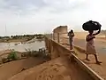 Deux jeunes piétons traversent le pont routier du Mali à Kidira, au Sénégal. À gauche le gué dans la rivière Faléme, 2017.