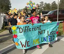 Des enfants portant une bannière, suivis par des adultes.