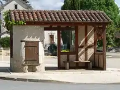 Puits et abri-bus sur la place du bourg.