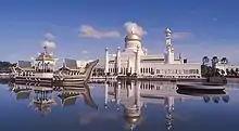 Vue de la mosquée Omar Ali Saifuddin depuis le lac. Un navire de cérémonie est accosté près de l'édifice.