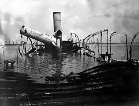 Photo en noir et blanc des restes d'un navire dépassant de la surface de l'eau