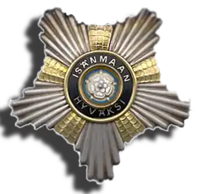Médaille de métal argenté, en forme d’étoile à cinq pointes ; au centre se trouve une rose émaillée en blanc sur fond turquoise ; autour de la fleur, un cercle émaillé noir porte en lettres dorées le texte suivant "Isämaan Hyväski".