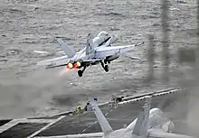 Un avion bi-réacteur, à double empennage, au décollage près de la mer.