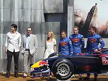 Photo d'officiels de Red Bull Racing et d'une monoplace bleue, célébrant un partenariat avec un film