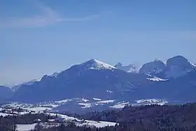 Vue hivernale depuis Cruseilles à l'ouest de la montagne de Cou (au centre) avec à droite les falaises du rocher des Tampes et de la roche Parnal et en arrière plan la pointe du Midi dans la chaîne du Bargy.