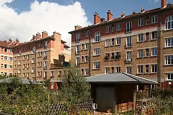 Photographie en couleur de jardins au premier plan et d'immeubles au second plan.