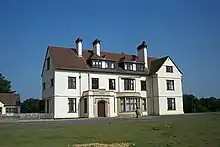 Photographie de Sutton Hoo House, maison blanche à deux étages avec toit rouge.