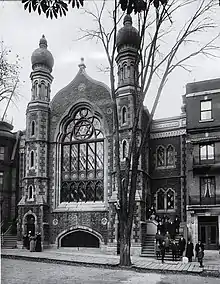 Une photo en noir et blanc de la façade de la veille synagogue en pierre avec deux tours et un grand vitrail.