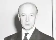 Joseph Szigeti, photographié en 1950, est cadré au niveau des épaules. Il porte un costume et une cravate. Il est chauve, sa lèvre inférieure est légèrement pendante. La photo est en noir et blanc, Szigeti est de face et regarde l'objectif.