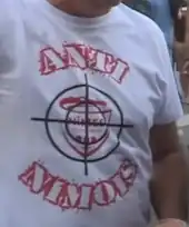Photographie d'un t-shirt blanc porté par un homme et par des inscriptions rouges.