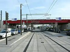 Sensiblement au même endroit que sur le cliché précédent, la RN 1 a été transformée par la création de la plate-forme de la ligne 5 du tramway d'Île-de-France, qui a été mise en service le 29 juillet 2013. La route conserve deux files de circulation dans chaque sens.