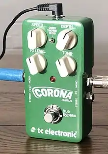 Photo d'une pédale d'effet rectangulaire verte, Corona Chorus, avec quatre potentiomètres blancs (Speed, Depth, FX Level, Tone), deux entrées et deux sorties jack et une prise d'alimentation