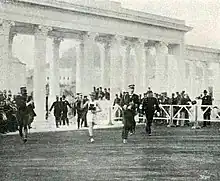 Un coureur portant un symbole de trèfle sur le ventre passe au milieu d'arches avec des colonnes.