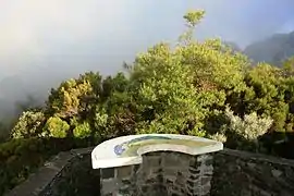 Une table d'orientation face à un paysage ennuagé des Hauts de La Réunion, France.
