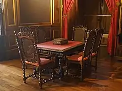 Photographie en couleur d'une table entourée de six chaises en bois.