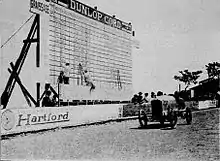 Photo d'un tableau d'affichage géant devant lequel passe une voiture.