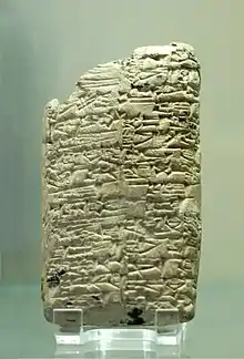 Photographie d'une tablette d'argile densément gravée de signes cunéiformes.