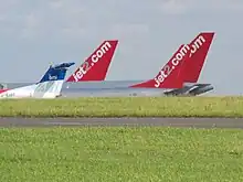 plusieurs dérives d'avion de ligne, visibles par-dessus un monticule. Chacune porte le nom d'une compagnie aérienne.