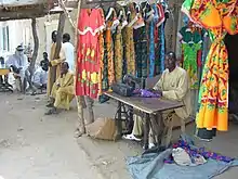 Photo d'un vendeur assis devant sa boutique ouverte sur la rue