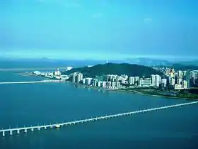 Vue de la côte nord de Taipa depuis la tour Macao sur la péninsule de Macao avec deux des trois chaussées reliant ces deux quartiers au premier plan ainsi que la piste de l'aéroport international de Macao au dernier plan.