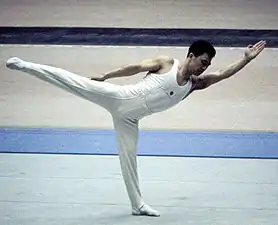 Un homme réalisant une figure de gymnastique sur un tapis.
