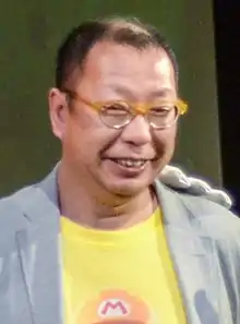Portrait d'un homme de type asiatique, très souriant, portant des lunettes.