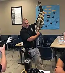 Un policier en uniforme brandit une ceinture de champion de catch.