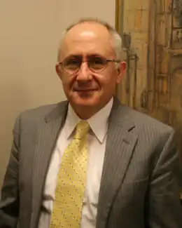 Photographie d'un homme portant un costume cravate et des lunettes.
