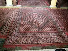 Gros plan sur l'un des tapis de la salle de prière. Ces derniers sont ornés de motifs géométriques. Le sol est revêtu de tapis alternant avec des nattes suivant les saisons.