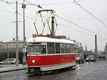 Un tramway de couleur crème à bande rouge en circulation.