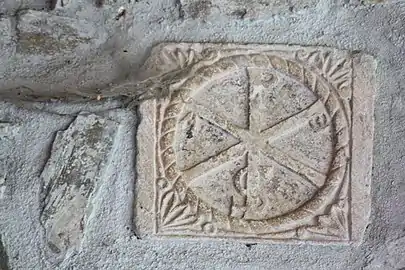 Un chrisme sculpté sur une pierre placée dans un mur de l'église.