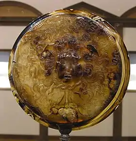 coupe ronde en pierre sculptée représentant la tête de Méduse.