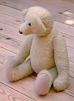 Ours en peluche blanc en position assise.