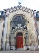 Bâtiment en pierre avec une porte surplombée d'une rosace.