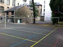 Photographie des terrains de sport du lycée Molière, et, au fond, une des façades du lycée et des bâtiments annexes.