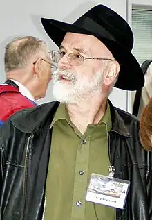 Photo d'un homme à la barbe blanche et portant un borsalino regardant vers la gauche.
