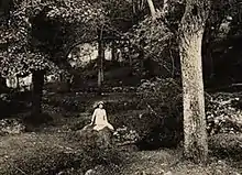 Photographie en noir et blanc d'une femme assise sur un rocher.