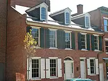 Photographie d'une maison en briques de trois étages donnant sur la rue