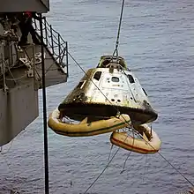Un vaisseau spatial est soulevé en l'air sur un navire.