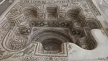 Vue du baptistère avec un côté endommagé et des fragments d'inscriptions