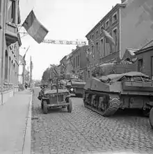 Dans une rue d’Antoing, le 3 septembre 1944, chars Sherman de la 5e division blindée des Gardes de l’armée de terre du Royaume-Uni croisant une jeep américaine durant les opérations de libération de la Belgique.